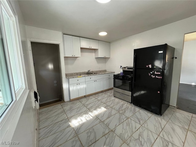 17005 Lipton Ave, Cleveland, OH 44128 - kitchen with freestanding refrigerator, stainless steel range with gas stovetop, white cabinetry, and light stone countertops