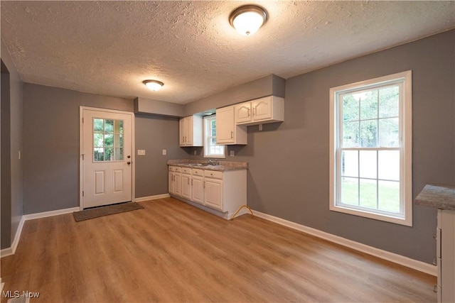 1022 Big Falls Ave, Akron, OH 44310 - kitchen with a textured ceiling, light wood-style floors, white cabinets, and healthy amount of natural light