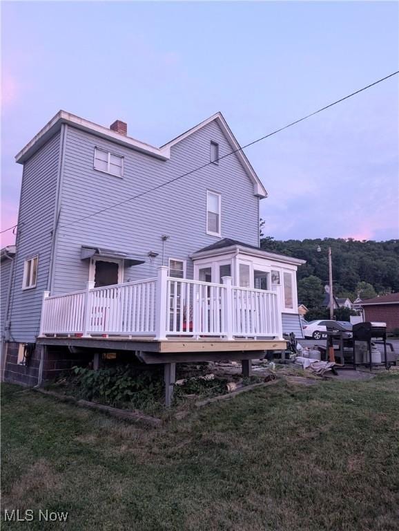 331 Louisiana Ave, Chester, WV 26034 - back of house at dusk featuring a chimney, a deck, and a lawn