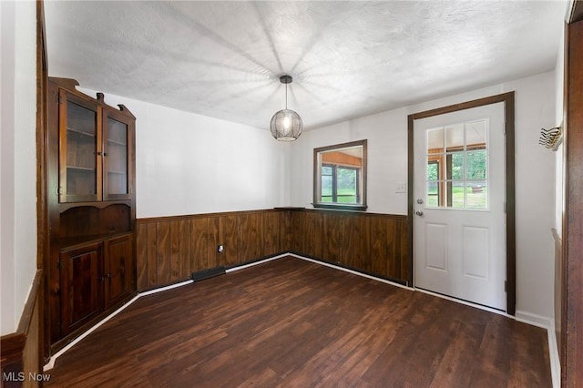 160 State St, Struthers, OH 44471 - unfurnished dining area featuring dark wood-type flooring, a wainscoted wall, wood walls, and a textured ceiling