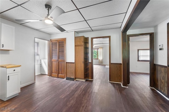 160 State St, Struthers, OH 44471 - kitchen featuring a ceiling fan, dark wood-style flooring, a wainscoted wall, white cabinets, and wood walls