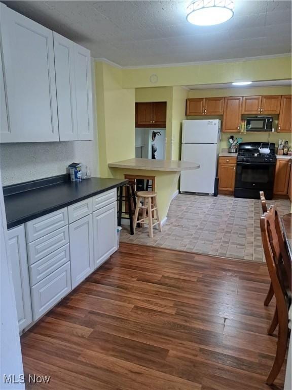 4016 State Route 7, Burghill, OH 44404 - kitchen with black appliances, light wood-style flooring, a breakfast bar area, and ornamental molding