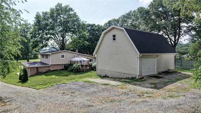 2463 NW Renner Dr NW, Dover, OH 44622 - view of side of home with an outdoor structure, a lawn, a gambrel roof, and view of scattered trees