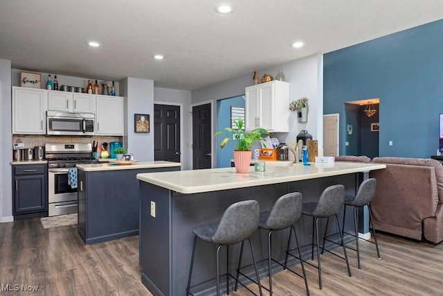 1005 Penn Ct, Grafton, OH 44044 - kitchen with appliances with stainless steel finishes, a breakfast bar area, white cabinets, dark wood-style floors, and light countertops