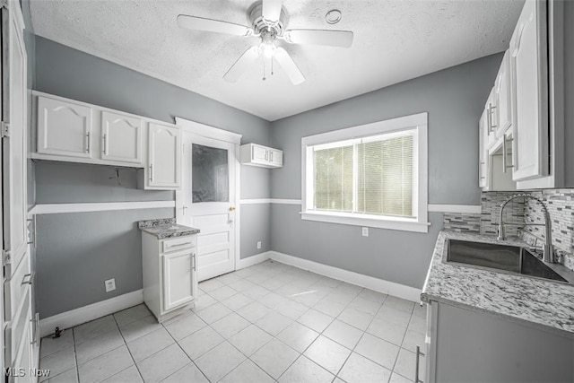 9907 Kempton Ave, Cleveland, OH 44108 - kitchen with a ceiling fan, a textured ceiling, backsplash, light tile patterned floors, and white cabinets