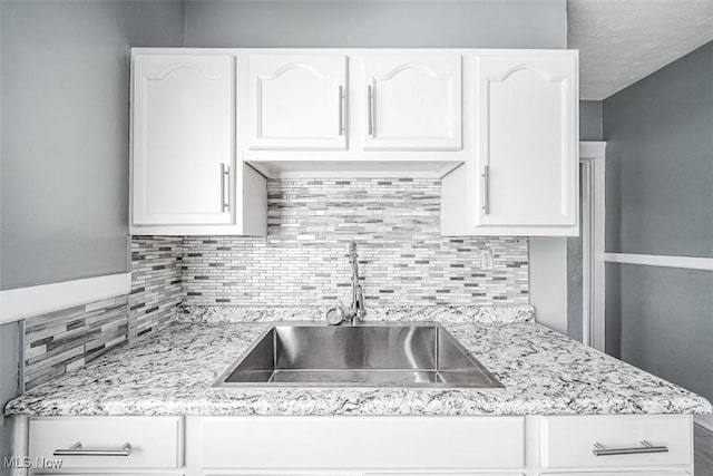 9907 Kempton Ave, Cleveland, OH 44108 - kitchen featuring white cabinets, tasteful backsplash, and light stone countertops