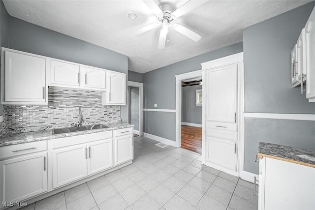 9907 Kempton Ave, Cleveland, OH 44108 - kitchen featuring a ceiling fan, decorative backsplash, white cabinetry, light tile patterned flooring, and a textured ceiling