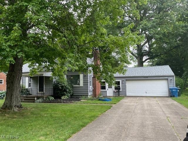 5559 Fitch Rd, North Olmsted, OH 44070 - view of property hidden behind natural elements with a garage, concrete driveway, a front yard, and a chimney