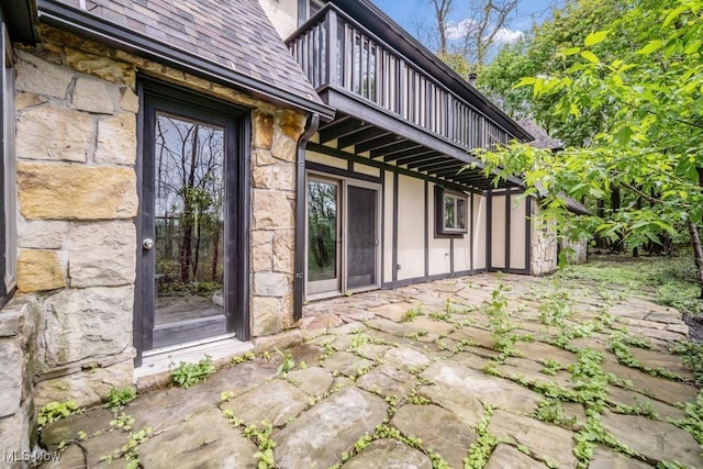 38038 Ridge Rd, Willoughby, OH 44094 - view of exterior entry with a balcony, stone siding, a patio, and a shingled roof
