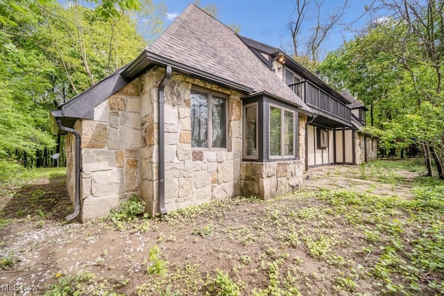 38038 Ridge Rd, Willoughby, OH 44094 - view of side of home featuring stone siding, a shingled roof, and a balcony