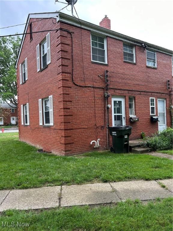 481 Kenwood Dr Unit N, Euclid, OH 44123 - view of home's exterior with a chimney, brick siding, and a lawn