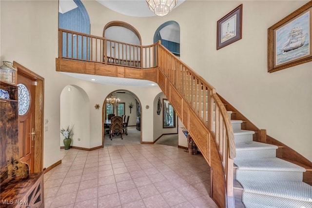 6869 Cliffside Dr, Vermilion, OH 44089 - stairway featuring a chandelier, arched walkways, tile patterned floors, and a high ceiling