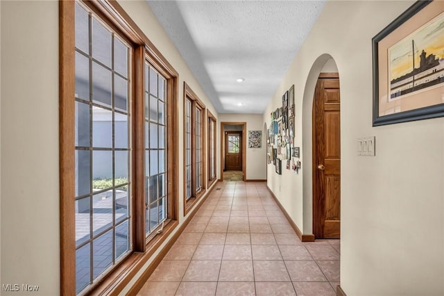 6869 Cliffside Dr, Vermilion, OH 44089 - hallway featuring arched walkways, light tile patterned floors, and a textured ceiling