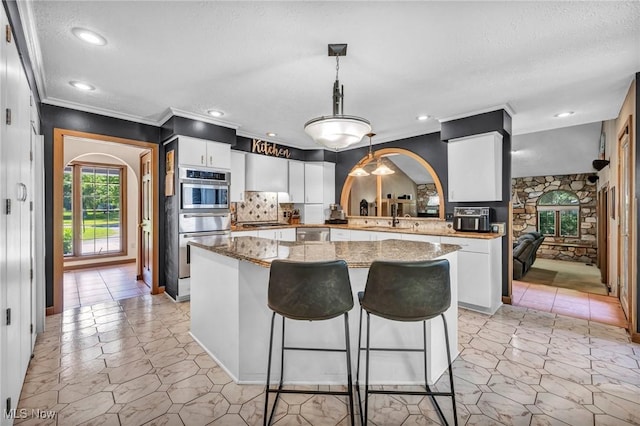 6869 Cliffside Dr, Vermilion, OH 44089 - kitchen with arched walkways, appliances with stainless steel finishes, a warming drawer, a kitchen island, and ornamental molding