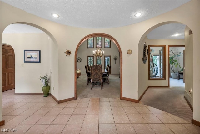 6869 Cliffside Dr, Vermilion, OH 44089 - foyer entrance with light colored carpet, light tile patterned floors, a textured ceiling, arched walkways, and a chandelier