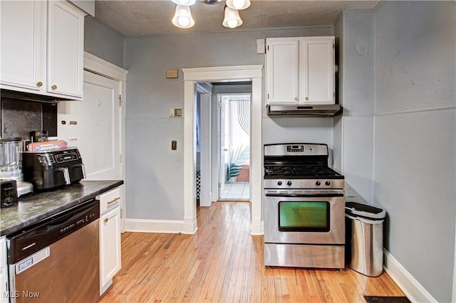 1289 W 115th St, Cleveland, OH 44102 - kitchen with appliances with stainless steel finishes, under cabinet range hood, white cabinets, dark countertops, and light wood finished floors