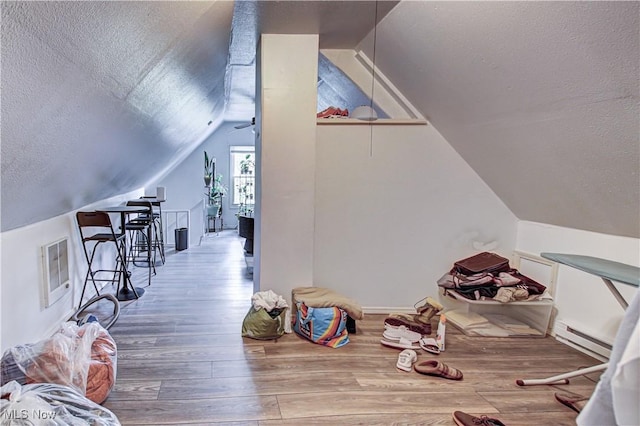 1289 W 115th St, Cleveland, OH 44102 - additional living space with a textured ceiling, a baseboard radiator, vaulted ceiling, and wood finished floors
