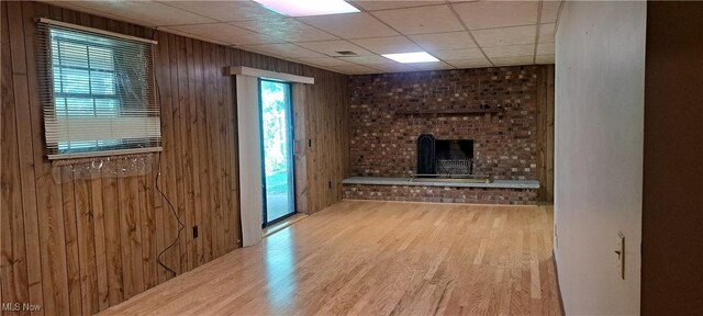 109 Hillview Dr, Charleston, WV 25314 - unfurnished living room with wood finished floors, wood walls, a fireplace, and a drop ceiling