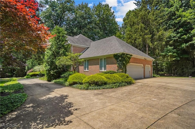 3773 N Shore Dr, Akron, OH 44333 - view of side of property with concrete driveway, brick siding, an attached garage, and roof with shingles