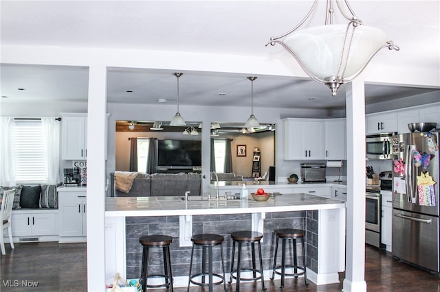 6221 Gault Rd, Canfield, OH 44406 - kitchen featuring stainless steel appliances, a kitchen breakfast bar, dark wood-style floors, white cabinetry, and hanging light fixtures