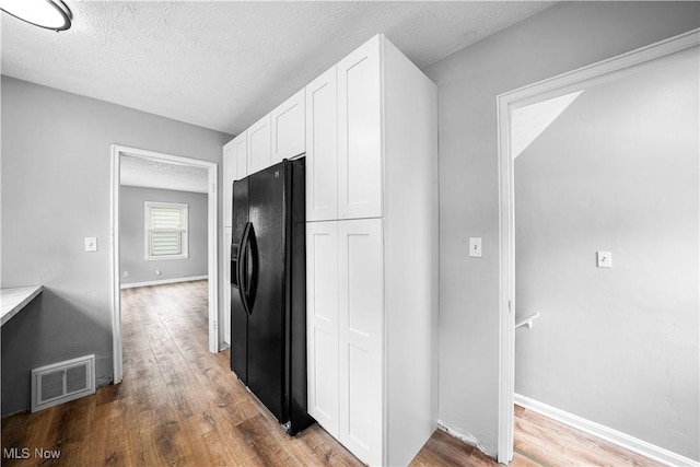 2405 Harding Rd, Cuyahoga Falls, OH 44223 - kitchen featuring black fridge, white cabinetry, wood finished floors, a textured ceiling, and light countertops