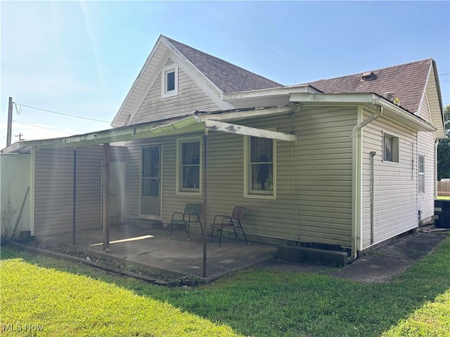 1209 Camden Ave, Parkersburg, WV 26101 - rear view of house featuring a patio, a lawn, and a shingled roof