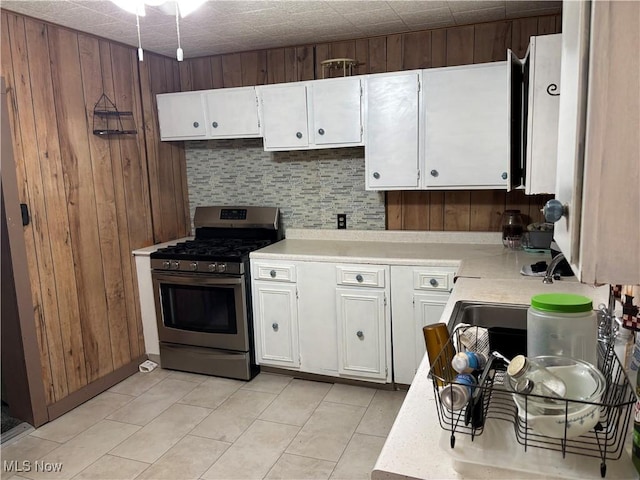 1209 Camden Ave, Parkersburg, WV 26101 - kitchen with gas stove, light countertops, white cabinetry, and wooden walls
