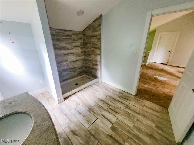 56612 Mcgee Rd, Shadyside, OH 43947 - bathroom featuring wood tiled floors, vaulted ceiling, and a tile shower