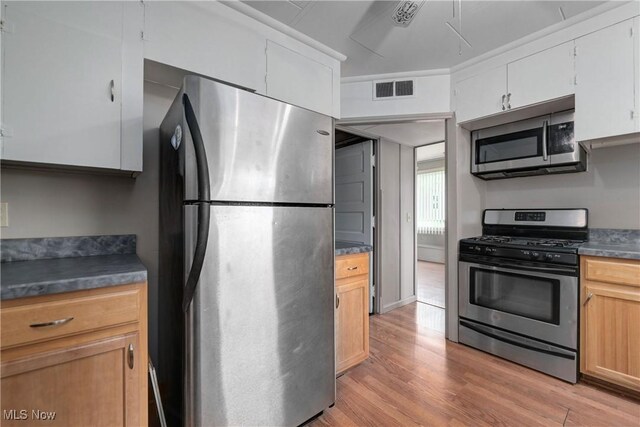 4465 Oberlin Ave, Lorain, OH 44053 - kitchen with stainless steel appliances, light wood-style floors, dark countertops, and white cabinets