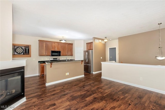 101 Stonegate Cir, Seven Hills, OH 44131 - kitchen featuring appliances with stainless steel finishes, dark wood finished floors, an island with sink, a multi sided fireplace, and a kitchen breakfast bar