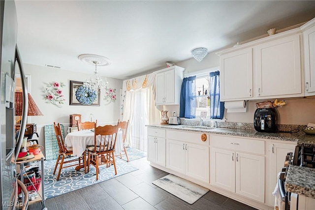 6470 Duncan Dr, Poland, OH 44514 - kitchen with gas stove, a chandelier, white cabinetry, and light stone counters