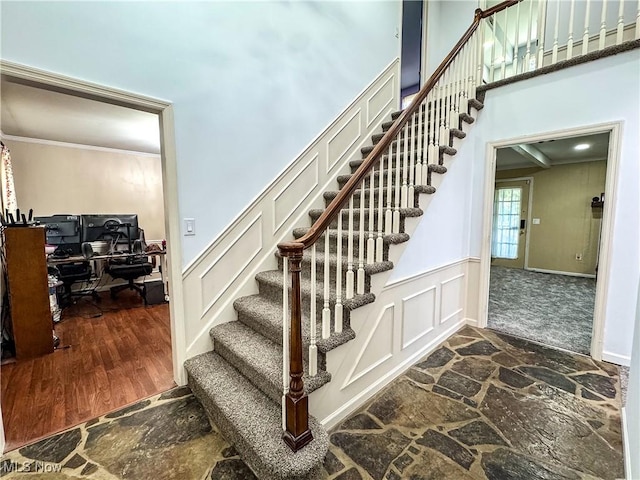 38 Lake Dr, Parkersburg, WV 26104 - stairs featuring stone floors, ornamental molding, a decorative wall, wainscoting, and a towering ceiling