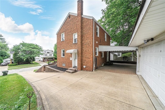 24690 Hawthorne Dr, Euclid, OH 44117 - view of side of home featuring brick siding, a carport, driveway, a chimney, and a garage