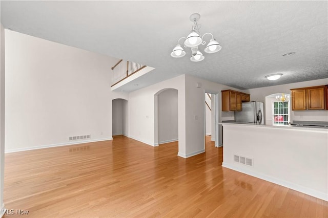 4877 Highland Place Ct, Richmond Heights, OH 44143 - kitchen with arched walkways, a chandelier, stainless steel refrigerator with ice dispenser, open floor plan, and brown cabinets