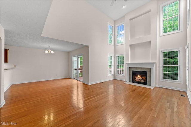 4877 Highland Place Ct, Richmond Heights, OH 44143 - unfurnished living room with a chandelier, light wood finished floors, a high ceiling, a tiled fireplace, and ceiling fan