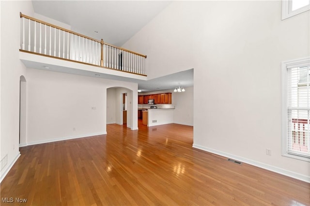 4877 Highland Place Ct, Richmond Heights, OH 44143 - unfurnished living room featuring arched walkways, a high ceiling, wood finished floors, and a chandelier