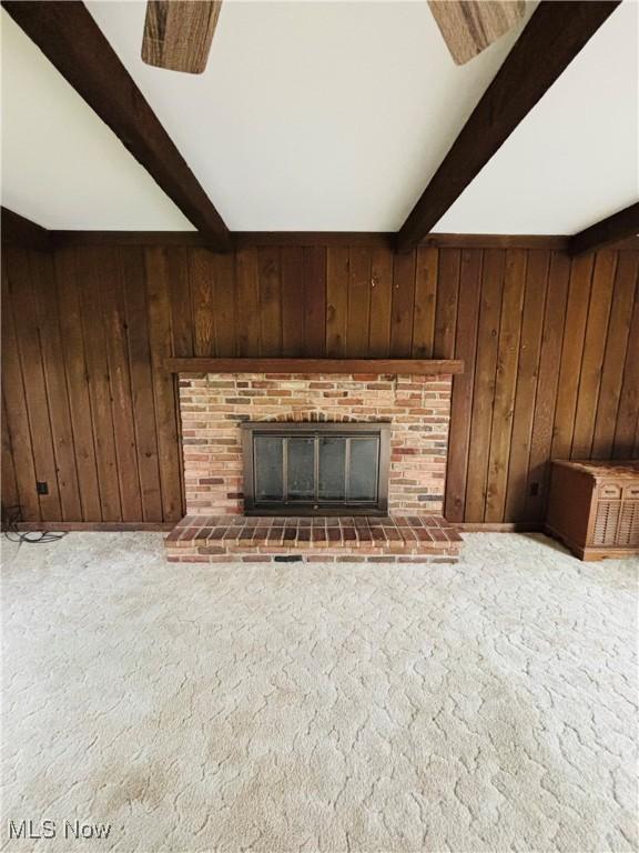 224 N Hills Dr, Parkersburg, WV 26104 - unfurnished living room featuring beamed ceiling, wood walls, a fireplace, and carpet floors