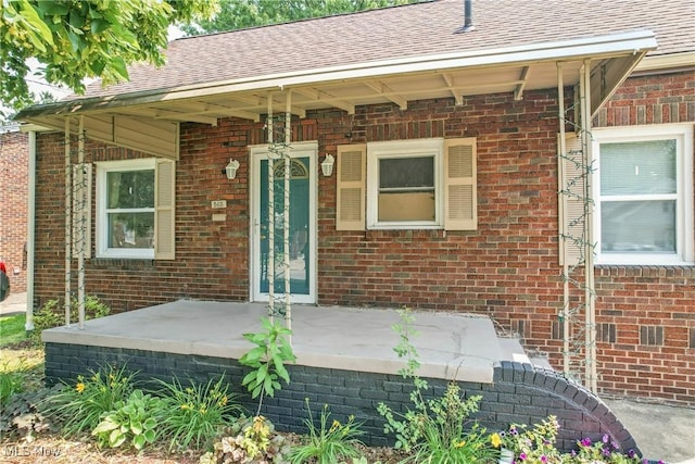 565 12th St, Campbell, OH 44405 - view of exterior entry featuring brick siding, a shingled roof, and a porch