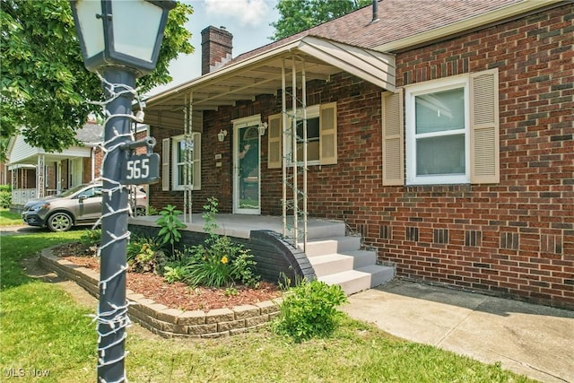565 12th St, Campbell, OH 44405 - doorway to property with covered porch, brick siding, a chimney, and roof with shingles