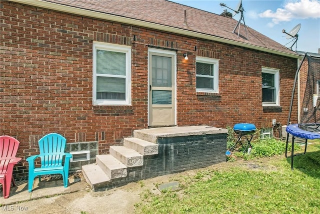 565 12th St, Campbell, OH 44405 - rear view of house with a trampoline, brick siding, roof with shingles, and a yard