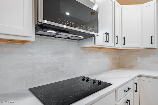 1404 15th St, Vienna, WV 26105 - kitchen with stainless steel microwave, black electric cooktop, white cabinets, and backsplash