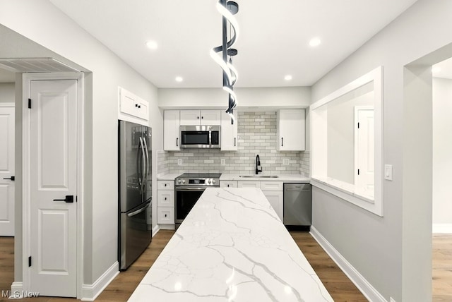 5830 Spotswood Dr, Lyndhurst, OH 44124 - kitchen featuring appliances with stainless steel finishes, wood finished floors, white cabinets, backsplash, and light stone countertops