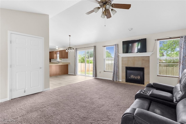 313 Crimson Cir, Campbell, OH 44405 - living area with vaulted ceiling, light colored carpet, a ceiling fan, a tiled fireplace, and light tile patterned flooring