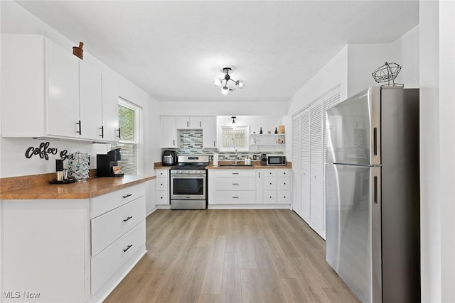 929 Moneta Ave, Aurora, OH 44202 - kitchen featuring appliances with stainless steel finishes, light wood finished floors, white cabinets, open shelves, and decorative backsplash