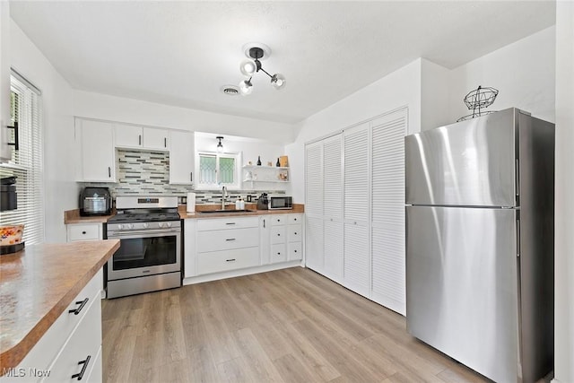 929 Moneta Ave, Aurora, OH 44202 - kitchen with stainless steel appliances, white cabinets, backsplash, and light wood-style flooring