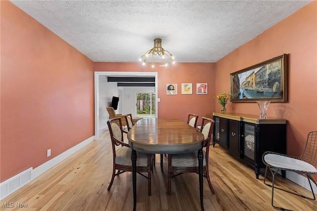 2632 S Green Rd, University Heights, OH 44122 - dining room featuring a chandelier, light wood-style flooring, and a textured ceiling