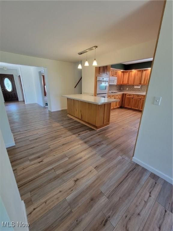 262 High St, Conneaut, OH 44030 - kitchen featuring white appliances, light wood finished floors, tasteful backsplash, and brown cabinets