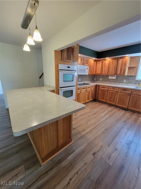 262 High St, Conneaut, OH 44030 - kitchen featuring white appliances, a peninsula, backsplash, and light countertops