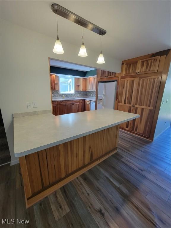 262 High St, Conneaut, OH 44030 - kitchen featuring white fridge with ice dispenser, a peninsula, dark wood-type flooring, brown cabinets, and light countertops