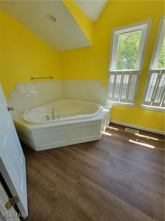 262 High St, Conneaut, OH 44030 - bathroom with lofted ceiling, a garden tub, and wood finished floors